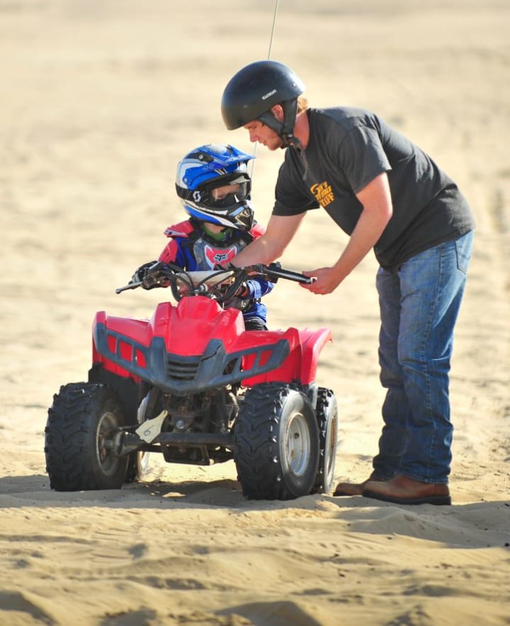 Staff teaching child how to ride an ATV at Pismo Beach