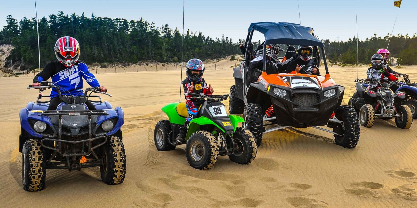 Children and adults, each on a different vehicle, at the Oregon Dunes location