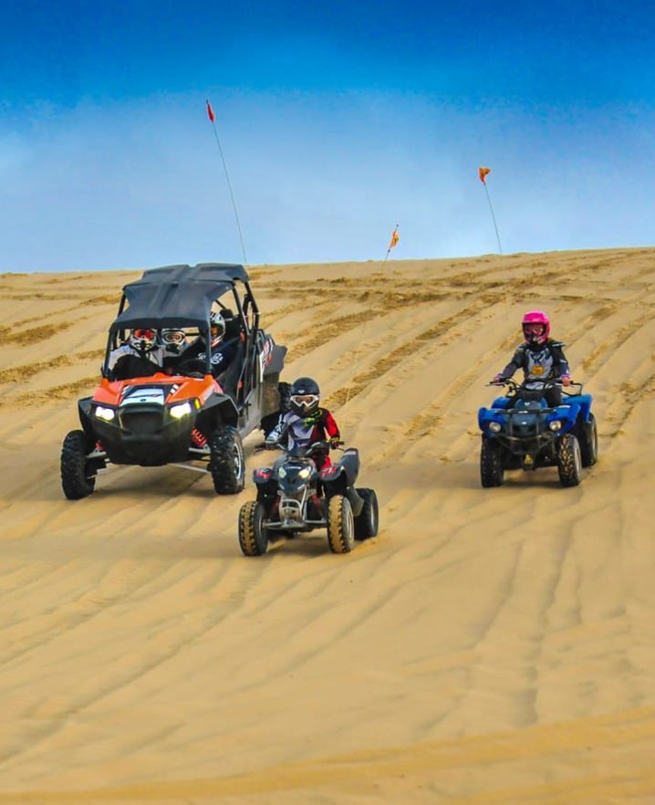 Family riding ATVs downhill in Oregon Dunes