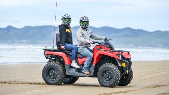 Two women riding an ATV by beach