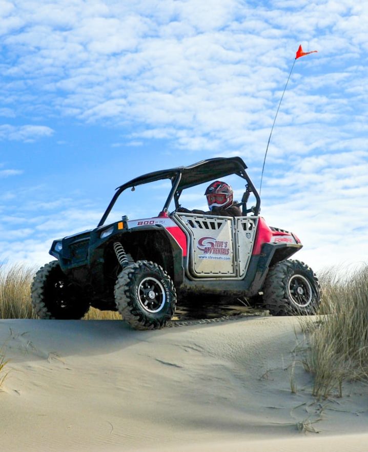 Guest riding Polaris RZR 800-4 through sand dunes in Oregon