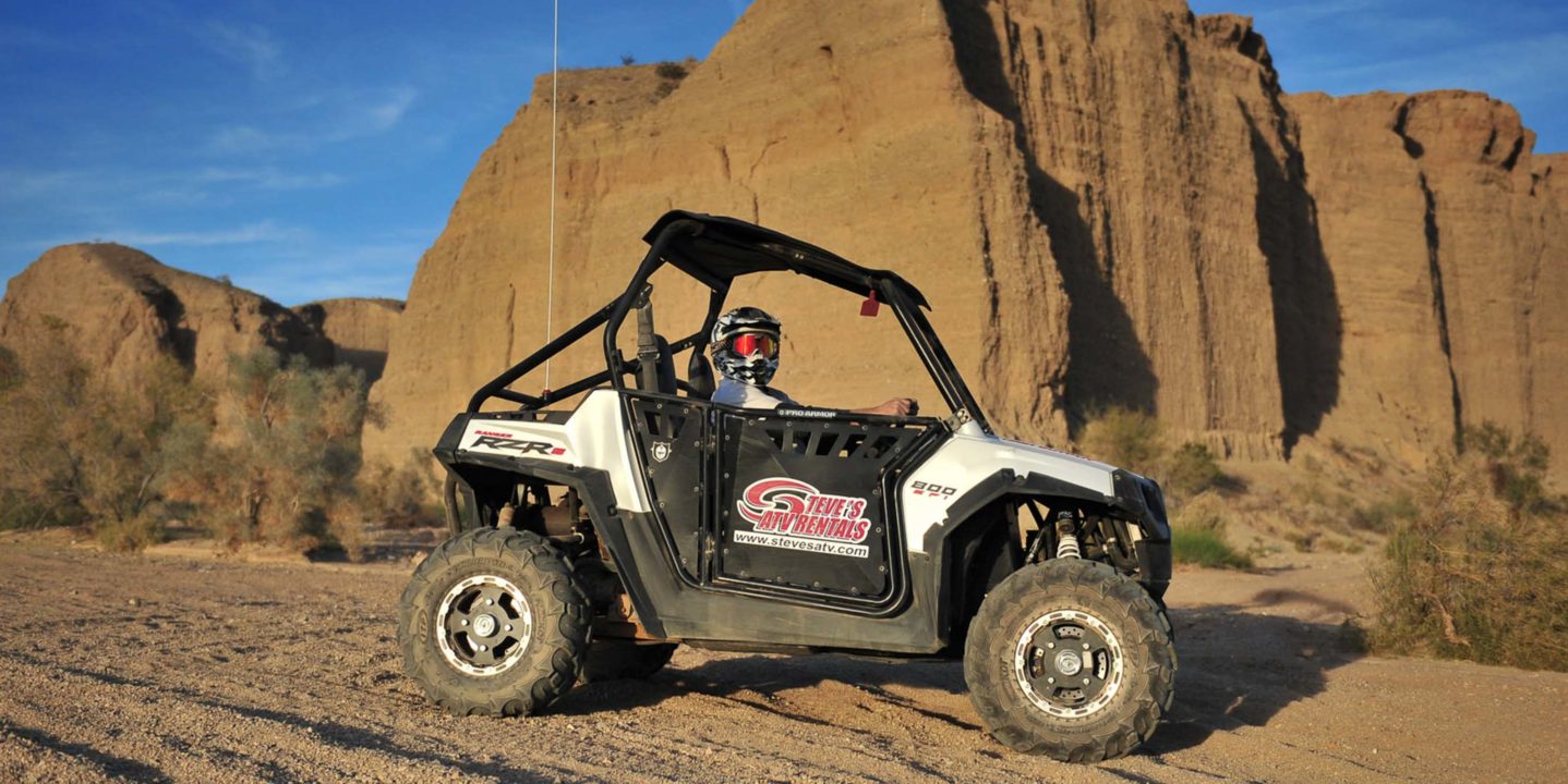 Child riding an Polaris RZR by rocky terrain