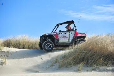 Guest riding a Polaris RZR 800-4 through grassy area